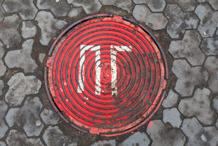 Red sewer manhole surrounded by decorative stone masonry. Abstract background and texture.の写真素材