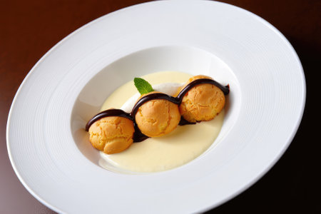 Three scoops of ice cream sit elegantly on a creamy sauce with chocolate drizzle. A sprig of mint...