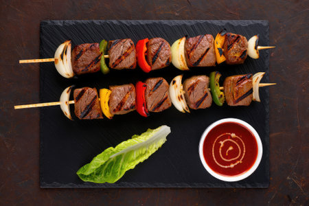 Juicy grilled beef skewers are arranged carefully with bell peppers, onions, and a fresh lettuce...