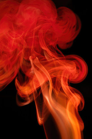 Bright and colorful flames swirl gracefully against a black background, creating a captivating visual display of fire. The intense reds and oranges evoke warmth and energy.の写真素材