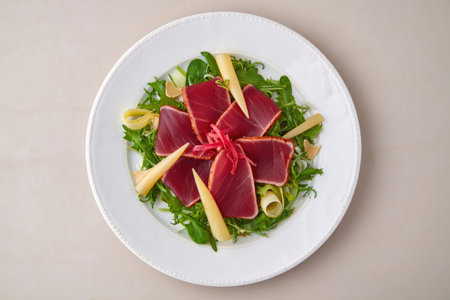 Seared tuna salad with arugula, pickled ginger, and cheese, beautifully presented on a white plate. A healthy and flavorful meal.の写真素材