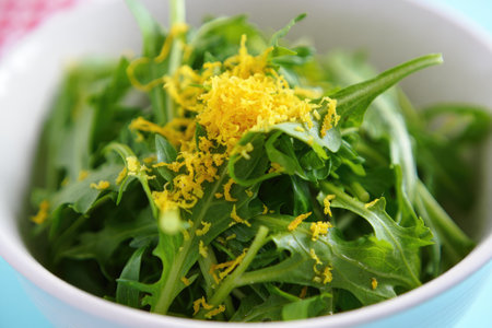 Arugula salad with fresh lemon zest, served in a white bowl. The close up shows the vibrant green leaves.の写真素材