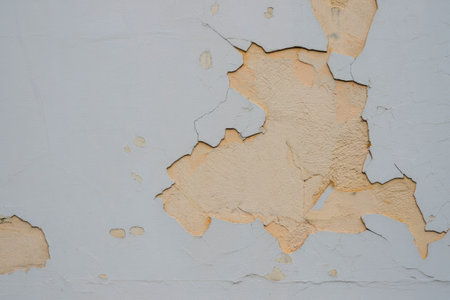 Close up of damaged wall with peeling paint, revealing the texture underneath. The textures and colors create an abstract feel.の写真素材
