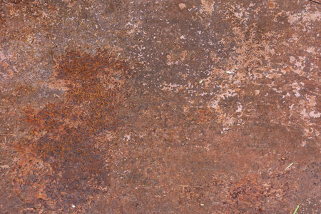 A close up view of a rusty metal surface with various textures and color variations, showing signs...