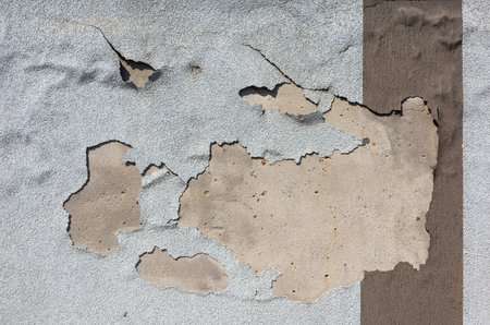 A close-up shot shows peeling paint revealing the concrete beneath. The texture and colors create an...