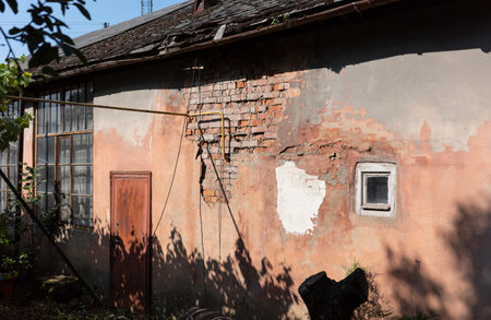 An old building with a weathered facade, showcasing a blend of brick and aged paint. The scene is bathed in sunlight and shadows.の写真素材
