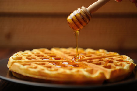 A golden Belgian waffle is drizzled with honey, creating a delicious and tempting breakfast scene. A...