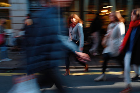 A woman with red hair and a scarf is seen walking on a street with other people, creating a sense of movementの写真素材