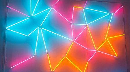 A dynamic arrangement of glowing neon tubes forms an intricate geometric pattern, featuring interconnected lines in bright pink, blue, yellow, and orange hues.の写真素材