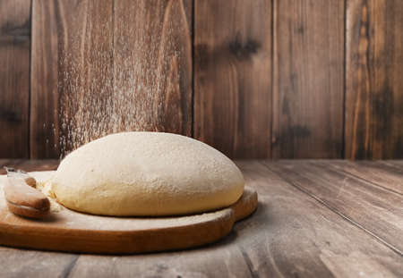 Raw dough with crumbling flour, on a wooden cutting board recipe idea for culinary photos