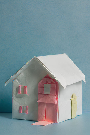 Paper house on a blue background. The concept of buying a new house.の写真素材