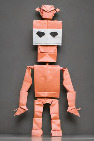 Funny robot made of crumpled paper on grey wall backgroundの写真素材