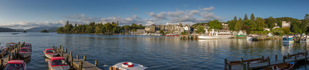 Bowness-on-Windermere, United Kingdom - September 7, 2015: Panoramic afternoon photo of Bowness-on-Windermere harbor with boats and pier in the foreground and the village and cruise ships in the backgroundのeditorial素材