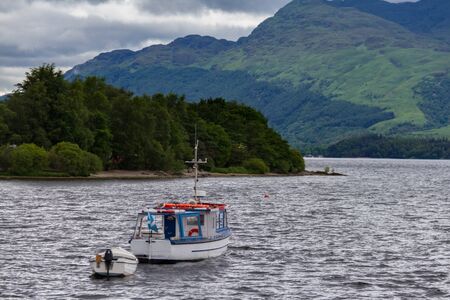 Loch Lomond scenery in Scotland with boats in the foreground. Photographed from Luss on a cloudy day.の写真素材