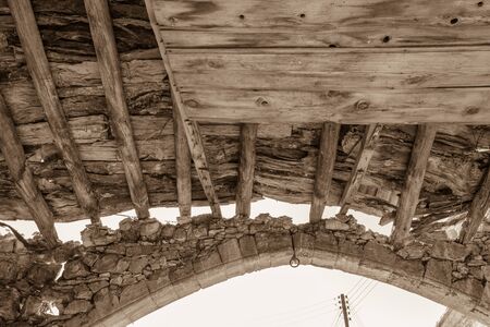 Wooden beams and stone arch of derelict building in Lofou, Cyprus. Sepia toned photoの写真素材