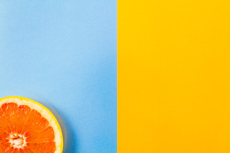 Top view of single grapefruit slice closeup on blue and yellow background. . Minimalist picture style with copyspace for textの写真素材