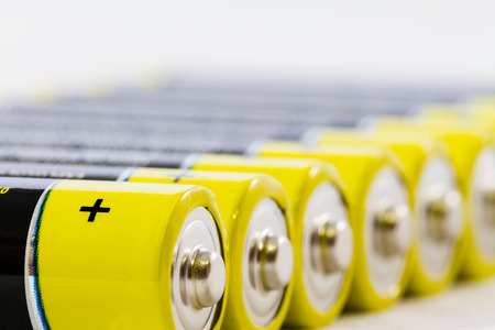 Diagonal row of yellow black AAA alkaline batteries isolated on a white backgroundの写真素材