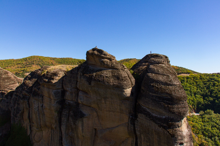 Spectacular view of two hikers on top of rocks at the Meteora rock monastery complex in Greeceの写真素材