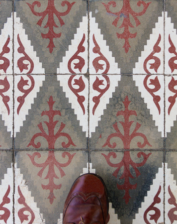 Top view of brown shoe of a man on tiled rhomboidal floor