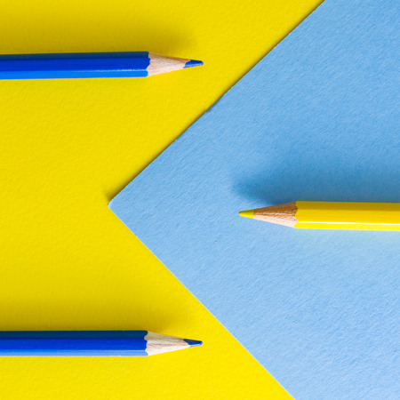 One yellow and two blue color pencils on yellow and blue background color papers. Minimalist composition.の写真素材