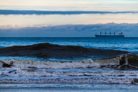 Tall waves and tanker in the distance off King Edward's Bay in Tynemouth, UK on a cold winter morningの写真素材