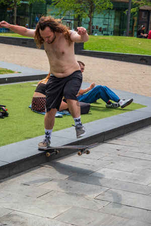 Manchester, United Kingdom - July 23, 2018: Man riding a skateboard as other people enjoy themselves in the sun on a hot summer day in Manchester city centreのeditorial素材