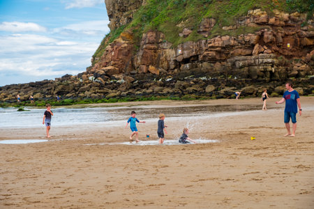 Tynemouth, England - August 2, 2018: Boys playing at King Edward's Bay beach on a hot partly cloudy summer day.のeditorial素材