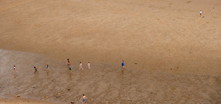 Tynemouth, England - August 2, 2018: Children playing happily on the beach at King Edward's Bay seen from a high viewpoint.のeditorial素材