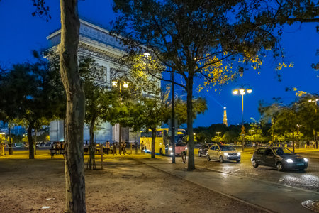 Paris, France - August 5, 2018: People and traffic passing by the Arc de Triomphe du Carrousel in Paris France at night with the Eiffel tower in the background. It was built to celebrate Napoleon's victories.のeditorial素材