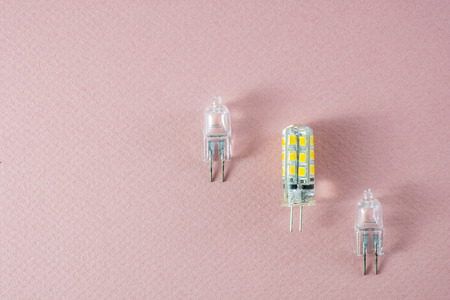 G4 bipin lamps two halogen and one modern eco LED type arranged diagonally on a pink background...