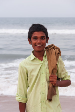 Chennai, India - September 6, 2007: A smiling local boy poses for a photo at Marina Beach in Chennai with the rough sea in the background.のeditorial素材