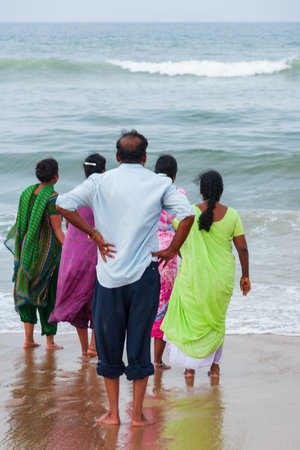 Chennai, India - September 6, 2007: One man and four women, barefooted,  gaze towards the rough sea at the popular Marina Beach in Chennaiのeditorial素材