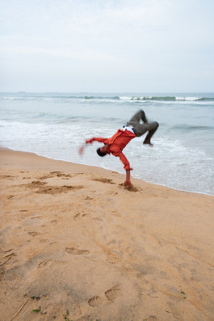 Chennai, India - September 6, 2007: Aman performs a somersault near the breaking waves of the rough...