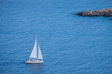 Aerial view of a sailing boat in the Mediterranean Sea as seen from Aphrodite hiking trail in Akamas peninsula, Cyprusの写真素材