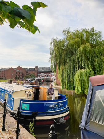 Manchester, United Kingdom - July 16, 2019: A lovely scenery of Castlefield, UK's first urban heritage park. A man seated in a narrowboat relaxes reading a book.のeditorial素材