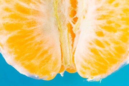 Sliced fresh Tangerine set against a blue backgroundの写真素材