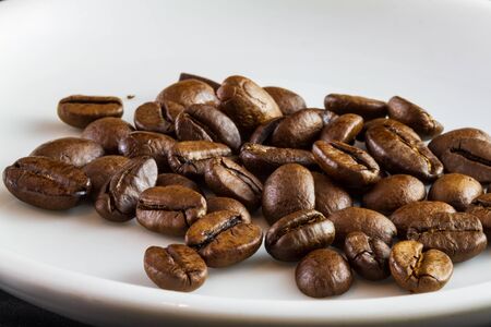 Macro capture of coffee beans in a white coffee cup