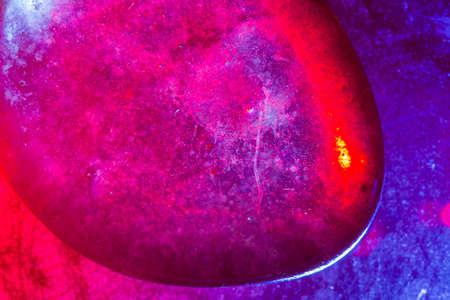 Tumbled mineral gem colorfully illuminated in macro capture showing abstract space-type details.