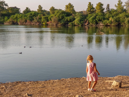 Athalassa Park, Cyprus - 9 October, 2020:  A girl plays happily by the lake at Athalassa natural park on a beautiful sunny autumn afternoon.のeditorial素材