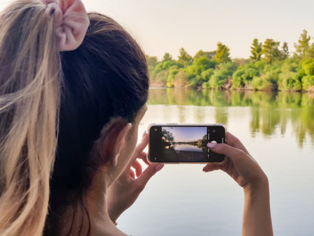 Athalassa Park, Cyprus - 9 October, 2020:  A girl takes a photo using her mobile phone of the lake...