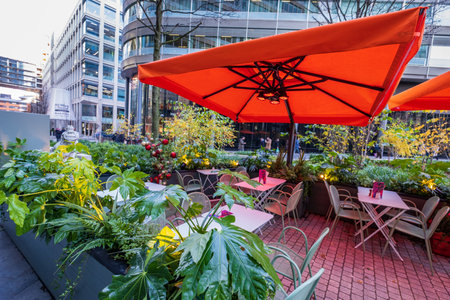Manchester, United Kingdom - November 29, 2019: Outdoor cafe with prominent orange umbrella in Spinningfields, a modern area specially developed in the 2000s as a business, retail and residential development of Manchesterのeditorial素材