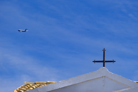 Church on the roof of a church and airliner flying in the distance in Corfu, Greeceの写真素材