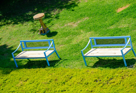 Blue benches and a side-table on grass at a park. Spring scene. Suitable as a backgroundの写真素材