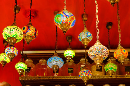 A vibrant display of hanging, spherical mosaic stained-glass lamps with intricate metalwork, characteristic of Middle Eastern decorative arts, in a retail setting.の写真素材