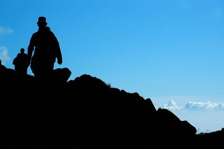 Silhouette of a climbers on blue backgroundの写真素材