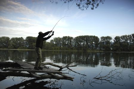 Silhouette of a fisherman at sunny day