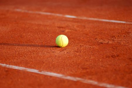 Tennis ball on a red courtの写真素材