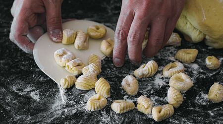 homemade potato gnocchis handmade with flour and egg on a black tableの写真素材