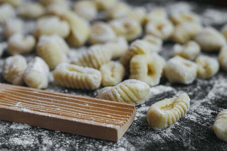 homemade potato gnocchis handmade with flour and egg on a black tableの写真素材