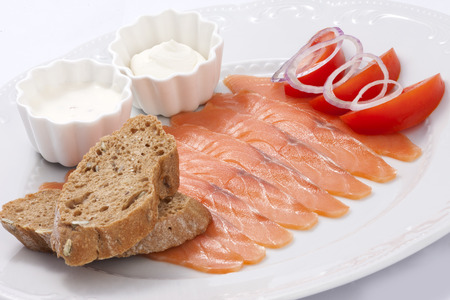 Mild salted salmon with sauce and toast decorated with tomatoes and onionsの写真素材